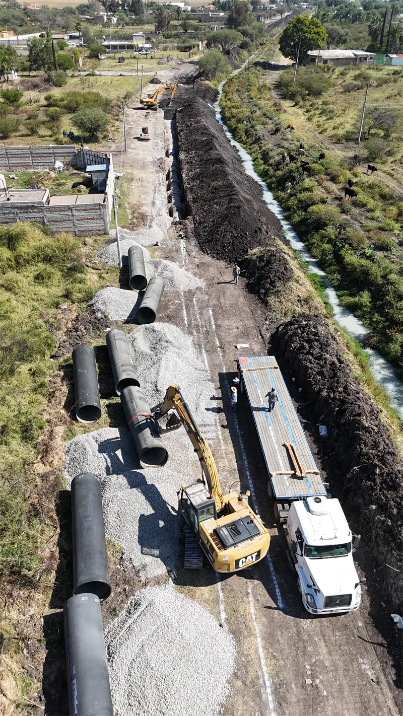 Vista aérea de la construcción de una línea de conducción con maquinaria y tubería a lo largo de la zanja